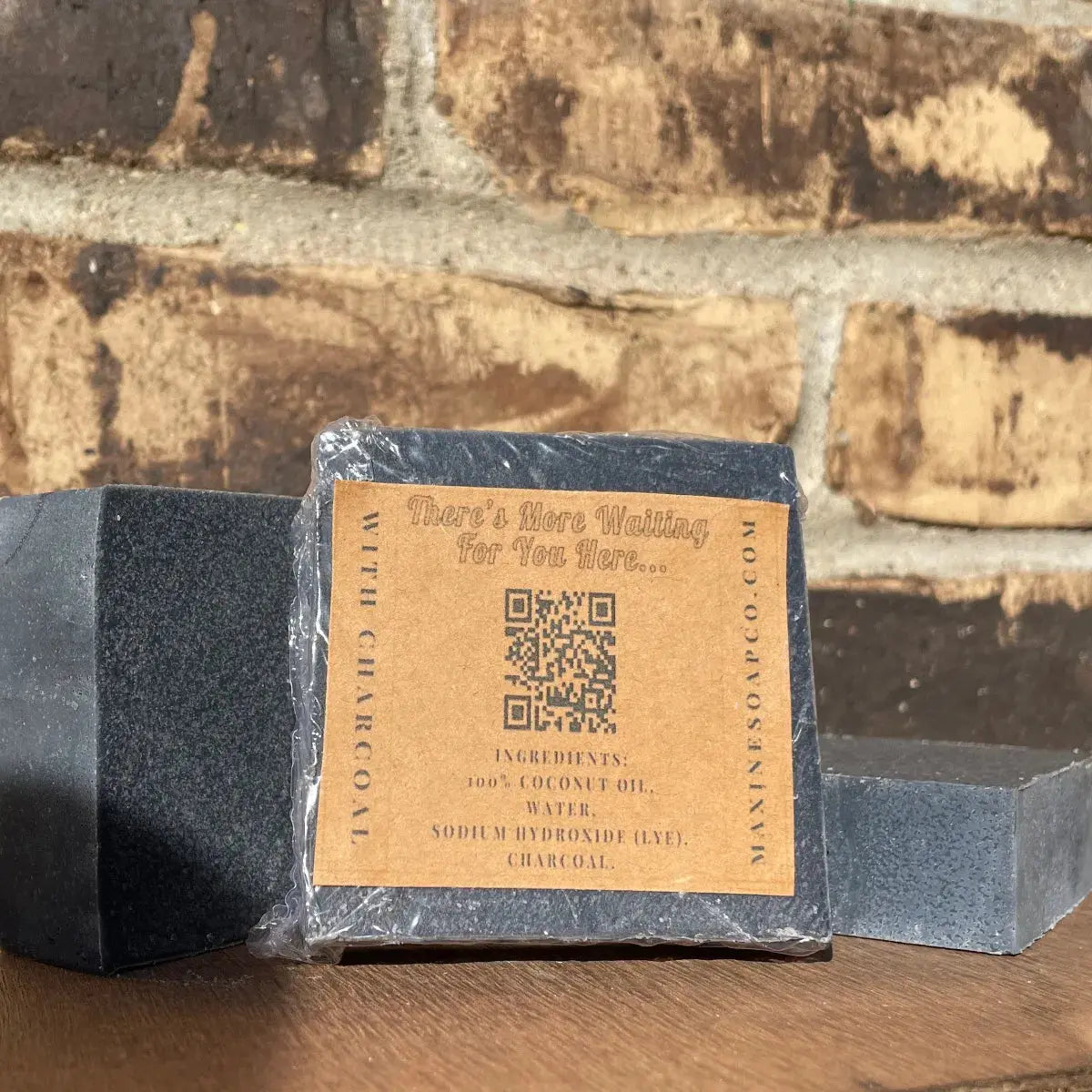 Back of wrapped Coconut Oil Charcoal Bar Soap by Maxine’s, 3.5 oz (99 g), label with ingredients and net weight.