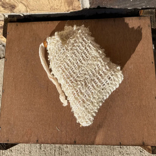 Textured sisal soap saver bag by Maxine’s with cord and wooden bead; holds a bar or scraps for lather and hang-dry use.